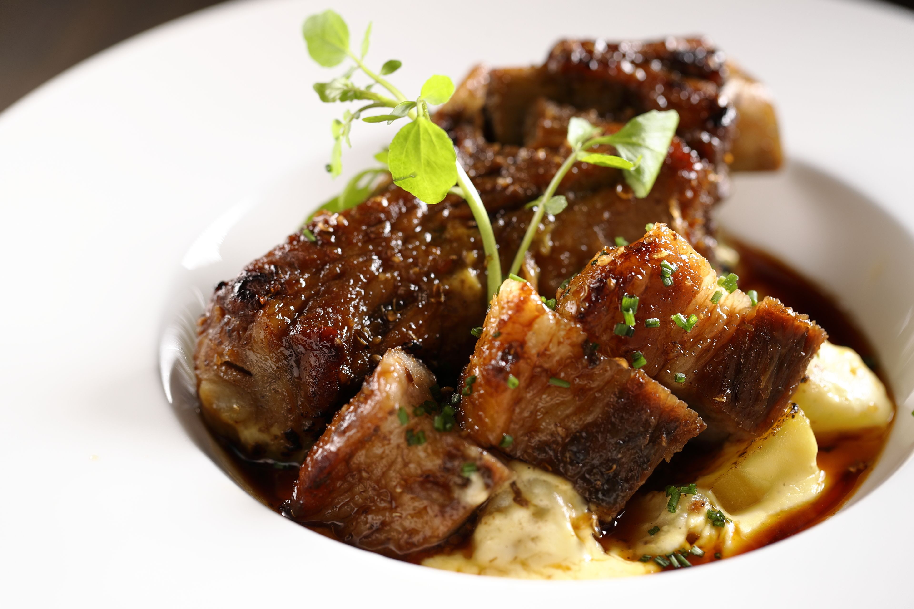 A dish with meat and potatoes garnished with herbs.
