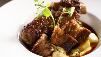 A dish with meat and potatoes garnished with herbs.