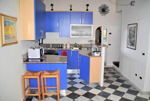 A kitchen with blue cabinets, a microwave, a stove, and a checkered floor.