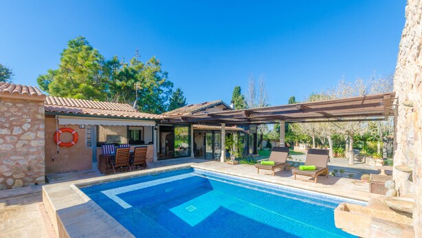 A swimming pool with a stone wall and a pergola.
