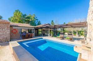 Ein Pool mit Steinmauer und einer Pergola.