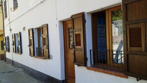 A row of white buildings with wooden shutters and a metal gate.