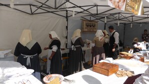 A tented market with tables displaying food items and a sign indicating a group of folkloristic Nuraxi figures.
