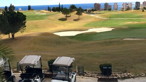 Un parcours de golf avec des bunkers de sable et une vue sur l’océan.