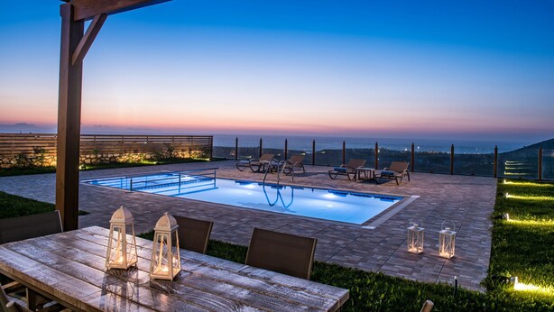 An outdoor pool area with a pergola, lounge chairs, and a table with lanterns. - Villa Arismari - "Oikos-your Cretan house" 5 mins drive from the beach (Aggeliana)