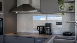 A modern kitchen with a stainless steel range hood, a coffee maker, and a built-in dishwasher. - Kalostous villa 2, Pool,Great location & Views (Agia Triada)