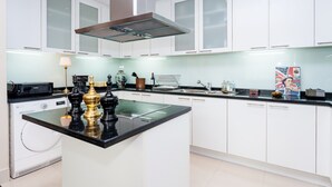 Una cucina moderna con mobili bianchi, un piano di lavoro nero e una lavatrice integrata.