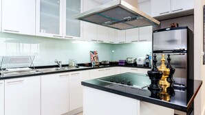Una cucina moderna con mobili bianchi, un piano di lavoro nero e un frigorifero in acciaio inossidabile.