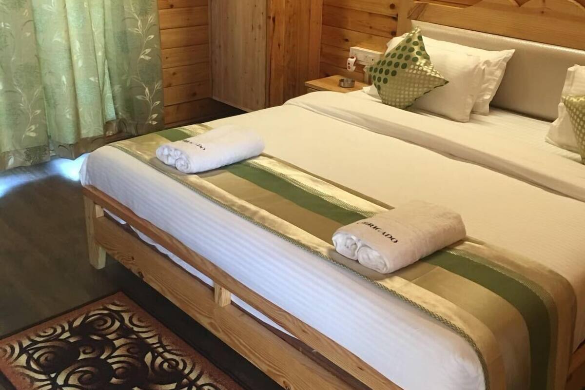 Ein Zimmer mit Holzboden, einem Bett, einem Schrank, einem Nachttisch und einem gemusterten Teppich.