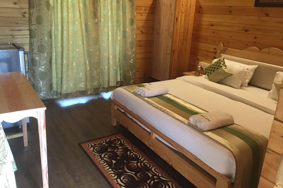Ein Zimmer mit Holzboden, einem Bett, einem Tisch und einem Kleiderschrank.