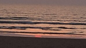 Un coucher de soleil sur une plage, avec des vagues.