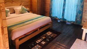 Une chambre dans une cabane en bois, avec un lit, une armoire et une fenêtre avec des rideaux.
