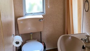 Pieni kylpyhuone, jossa on wc, pesuallas ja ikkuna.