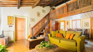 Ein rustikaler Innenraum mit einer Holztreppe, einem grünen Sofa und einem Holztisch.