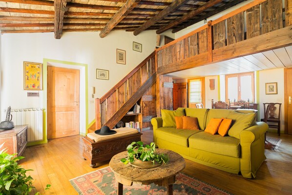 A rustic interior with a wooden staircase, a green sofa, and a wooden coffee table.
