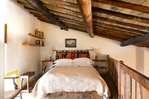 A bedroom with a wooden bed, a sloped ceiling, and a view of the outdoors.