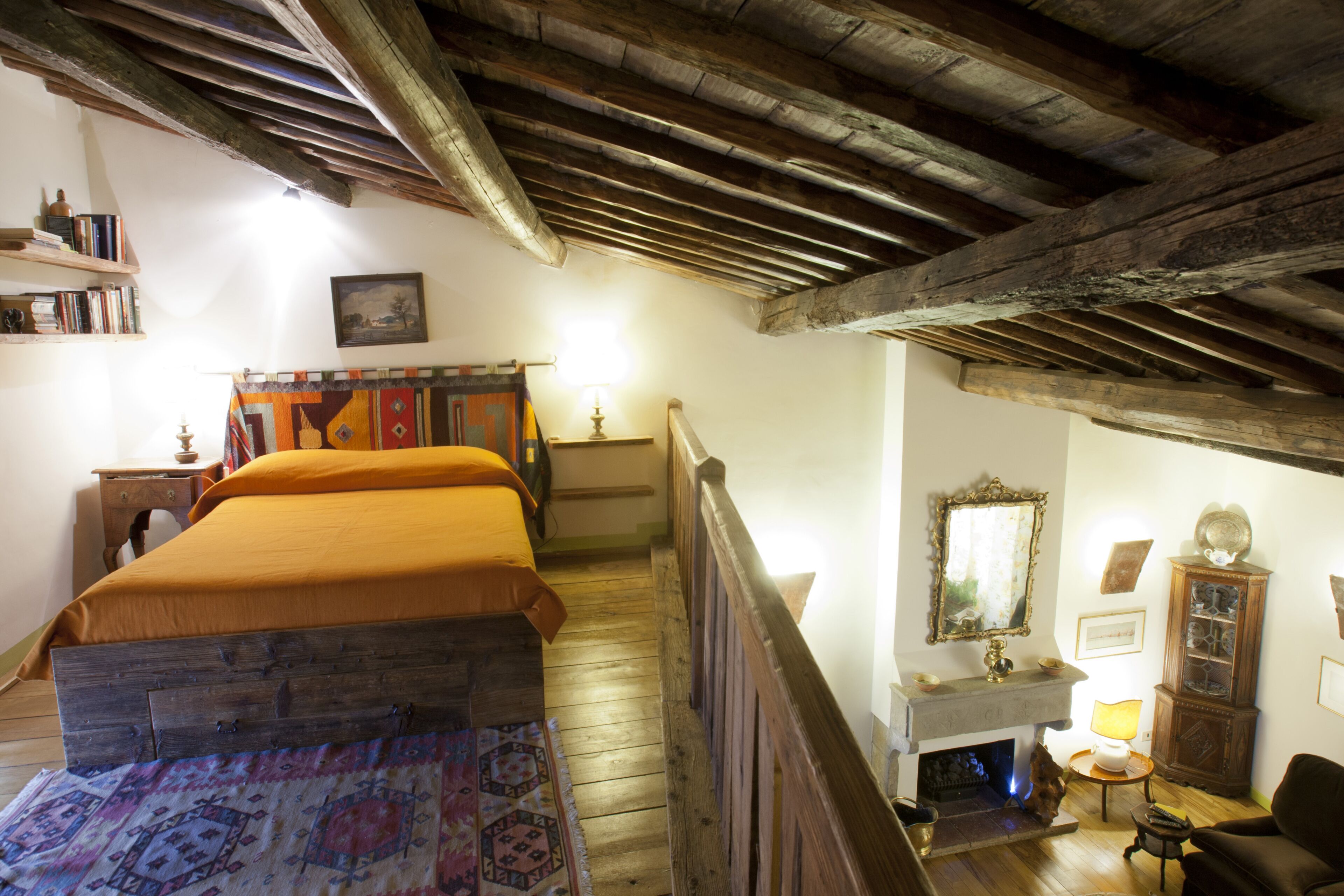 A traditional room with a wooden bed, a fireplace, and a wooden staircase.