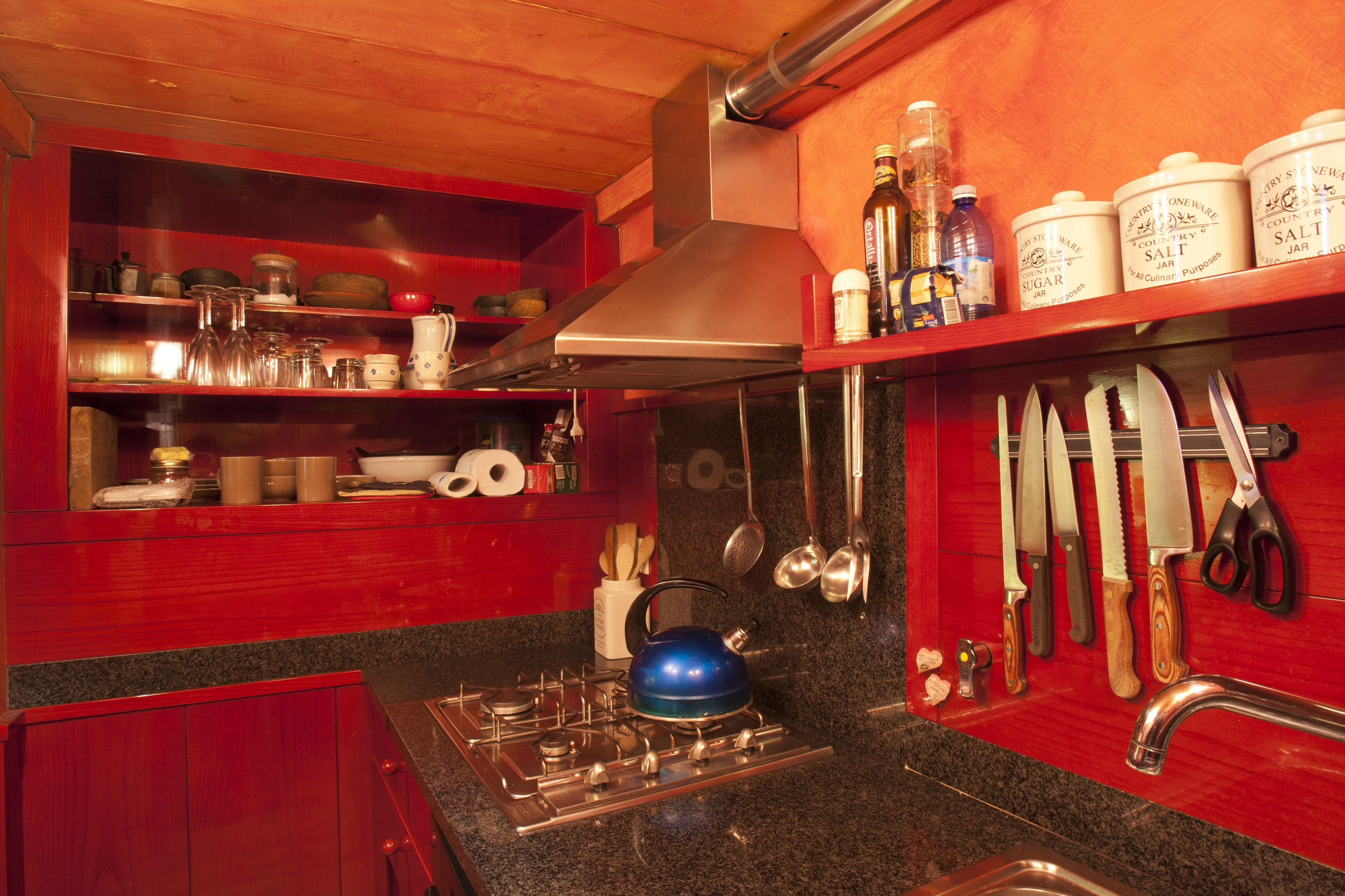 A kitchen with a gas stove, stainless steel sink, and wooden cabinets.