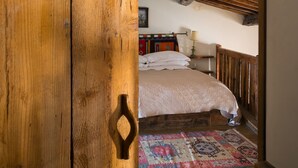 Ein rustikales Zimmer mit Holzboden, einem Bett, einem Schrank aus Holz und einem gemusterten Teppich.