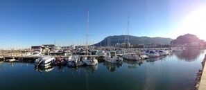 A marina with various boats docked, a clear sky, and a mountain in the background.
