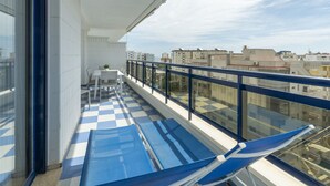 A balcony with a checkered floor, a table with chairs, and a blue chair.