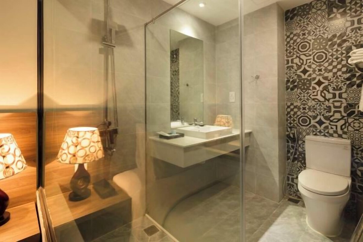 A modern bathroom with a glass shower enclosure, a white sink, and a patterned wall.