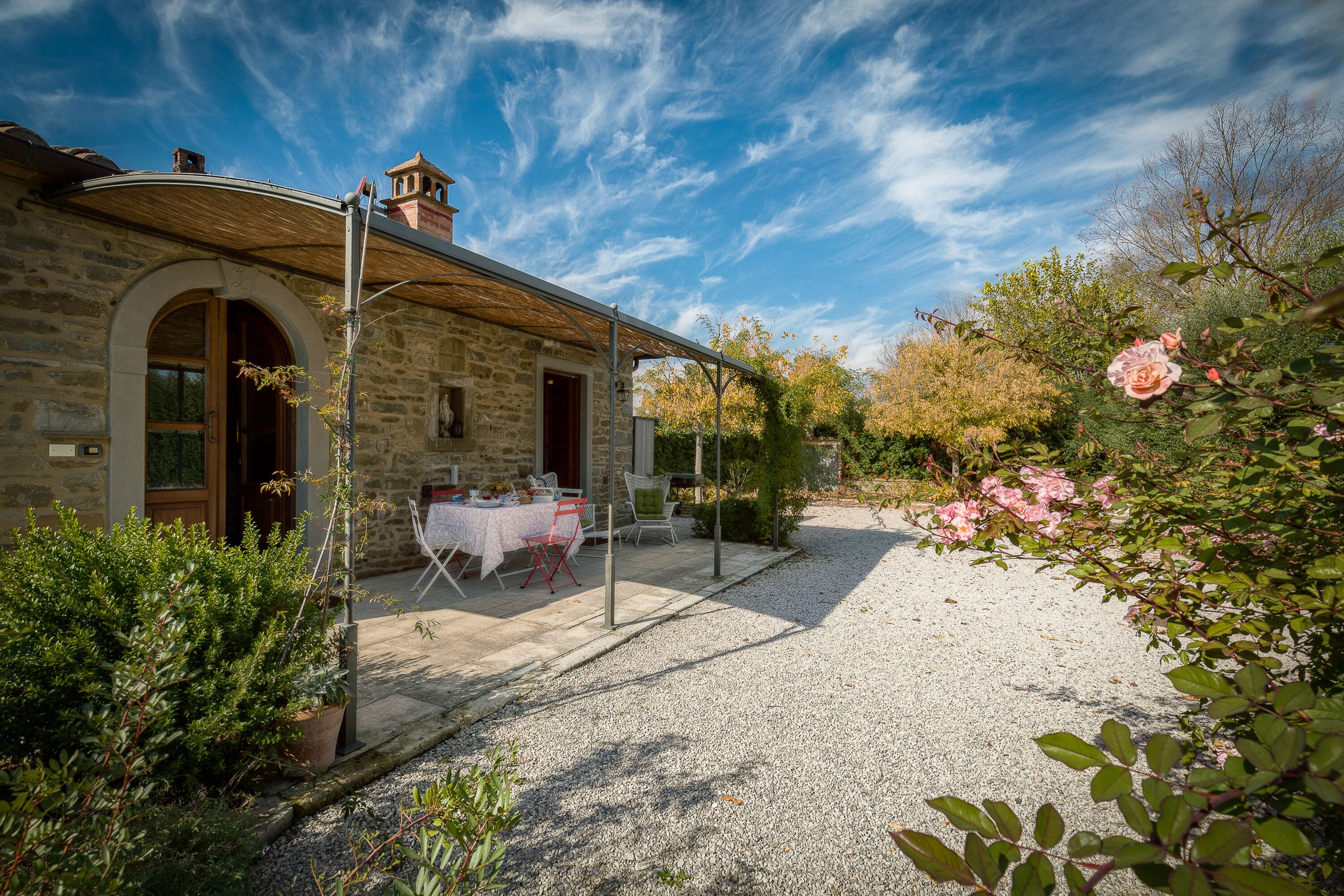 A stone building with a covered patio, outdoor seating, and a gravel path.
