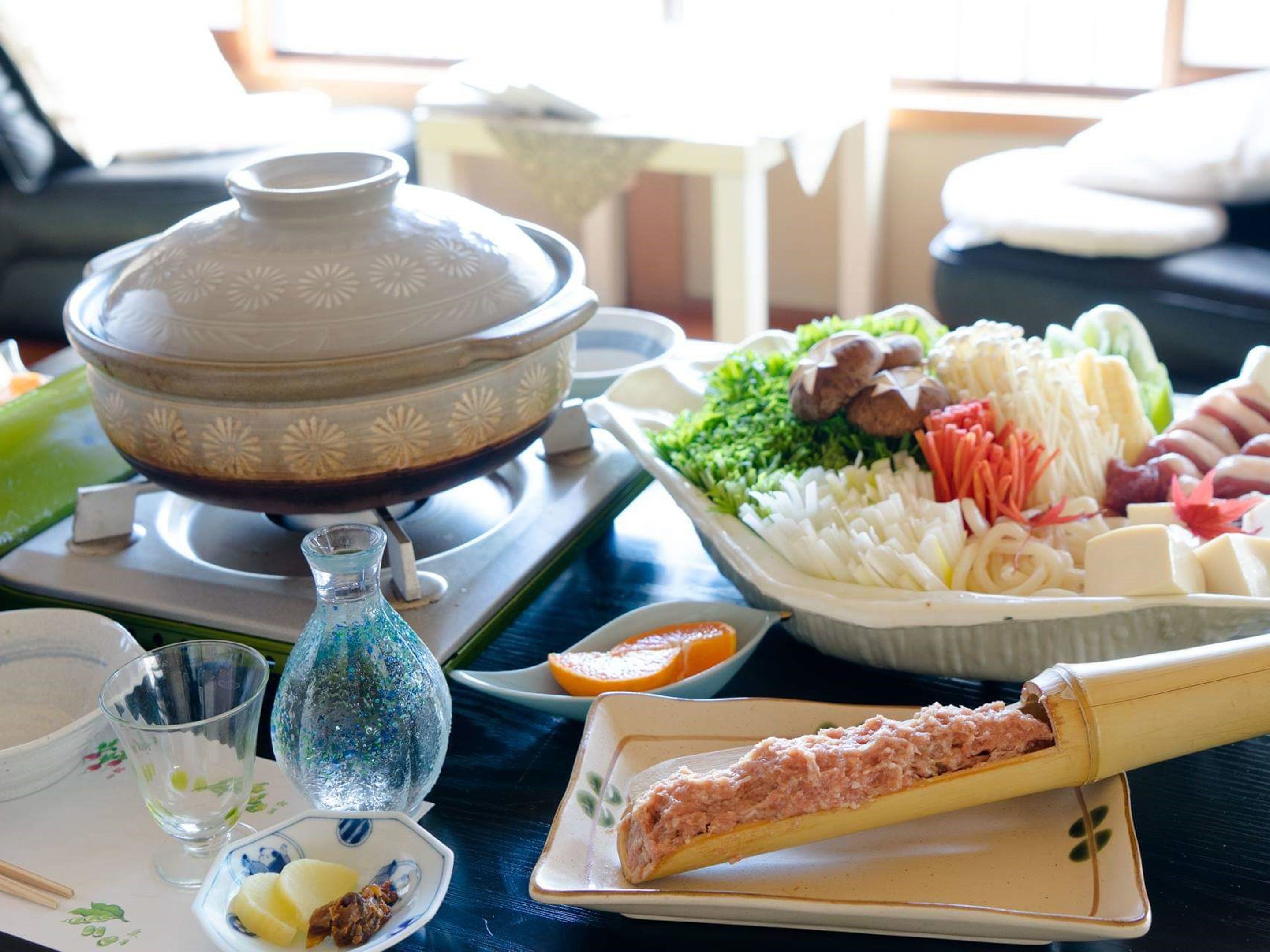 A traditional Japanese meal setup with a hot pot, various vegetables, and a dish of fish.
