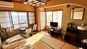 A room with tatami mats, a television, a small table, a sofa, and a view of the city. - Shiroyama inn (Ikoma)