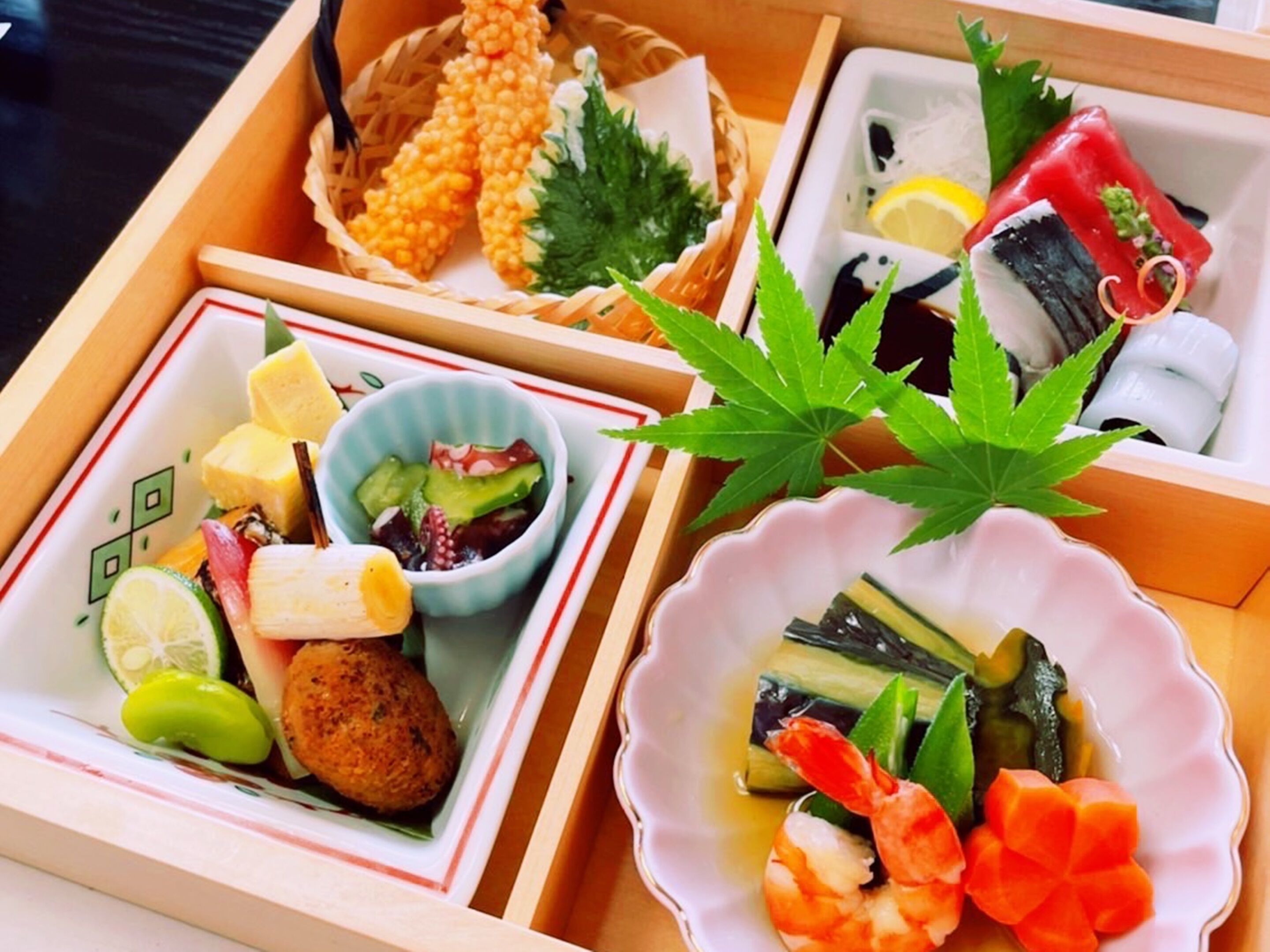 Un plateau en bois comportant trois compartiments contenant divers aliments, notamment des fruits de mer, des légumes et un bol de salade.