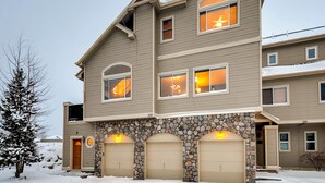 A multi-story residential building with a stone facade, multiple windows, and a garage.