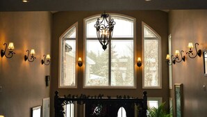 A hallway with large arched windows, wall sconces, and a chandelier. - water front luxury lake house (Janetville)