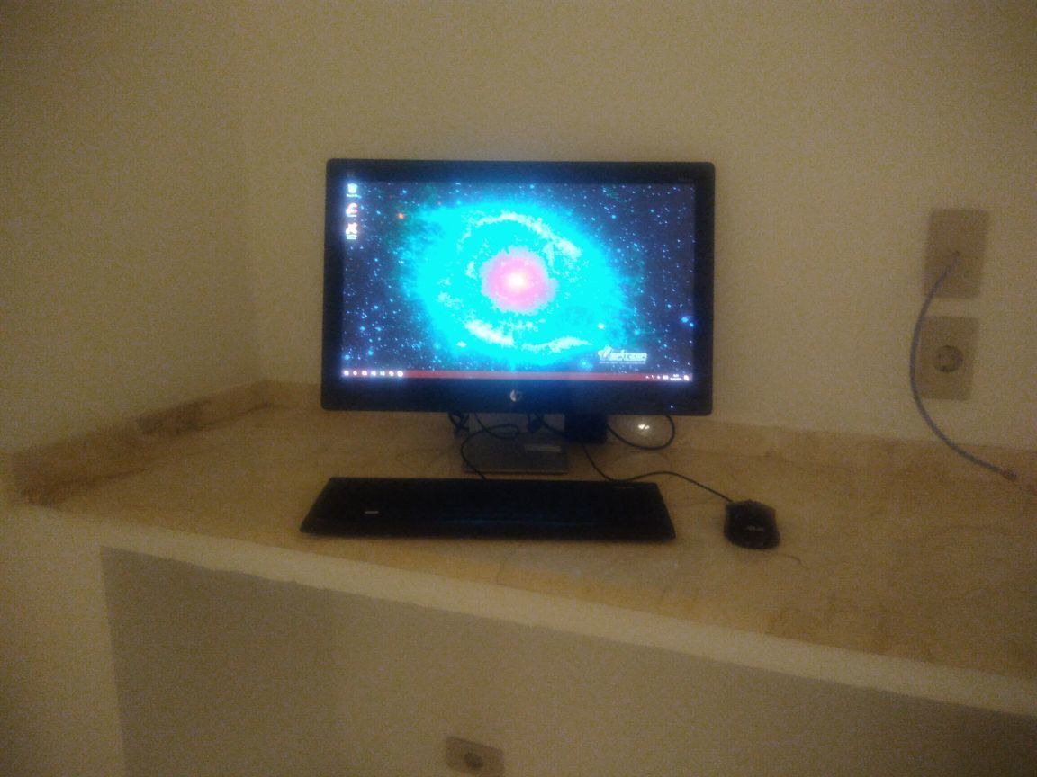 Un écran d’ordinateur affichant une image de galaxie, posé sur un bureau.
