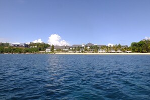 Un hôtel situé sur la côte, composé de plusieurs bâtiments, avec une plage et des palmiers.
