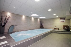 A spa area with a rectangular pool, a waterfall feature, and a seating area with a bench and a small table. - Résidence Green Marsh S2 (Strasbourg)