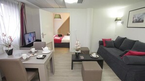 Una habitación de hotel moderna con comedor, sofá y cama.