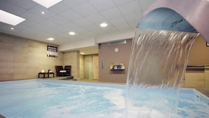 Una piscina con un elemento acuático, un reloj en la pared y un cartel con instrucciones de emergencia.
