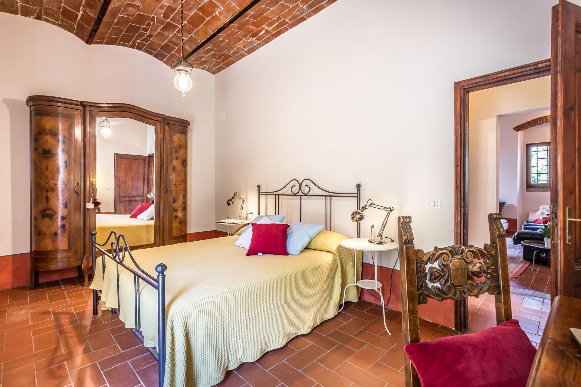 Un dormitorio con cama, mesita de noche, lámpara y una silla de madera.