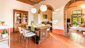 Un comedor con techo de ladrillo, una mesa de madera con sillas y un aparador con puertas de cristal.