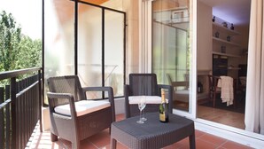 A balcony with wicker furniture, a bottle of champagne, and a glass.