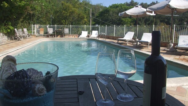 A pool area with lounge chairs, a bottle of wine, and two glasses on a wooden table. - Villa il Castagno - Three Bedroom Villa, Sleeps 11 (Val Canina)