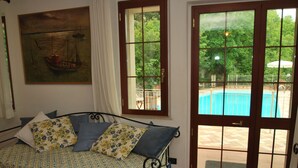 A bedroom with a bed, a painting, and a view of an outdoor swimming pool through a glass door. - Villa il Castagno - Three Bedroom Villa, Sleeps 11 (Val Canina)