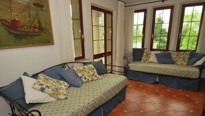 A room with two beds, a painting of a boat on the wall, and large windows with curtains. - Villa il Castagno - Three Bedroom Villa, Sleeps 11 (Val Canina)