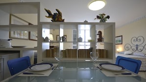 Un coin repas avec une table en verre, deux chaises et une sculpture de poisson décorative placée au-dessus de la table.