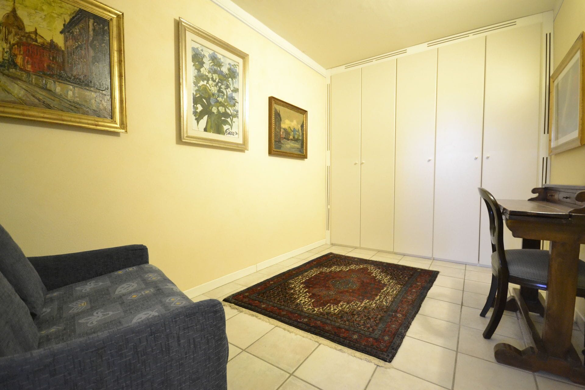 Une pièce comprenant un canapé, une table à manger avec des chaises, un tapis à motifs et une armoire.
