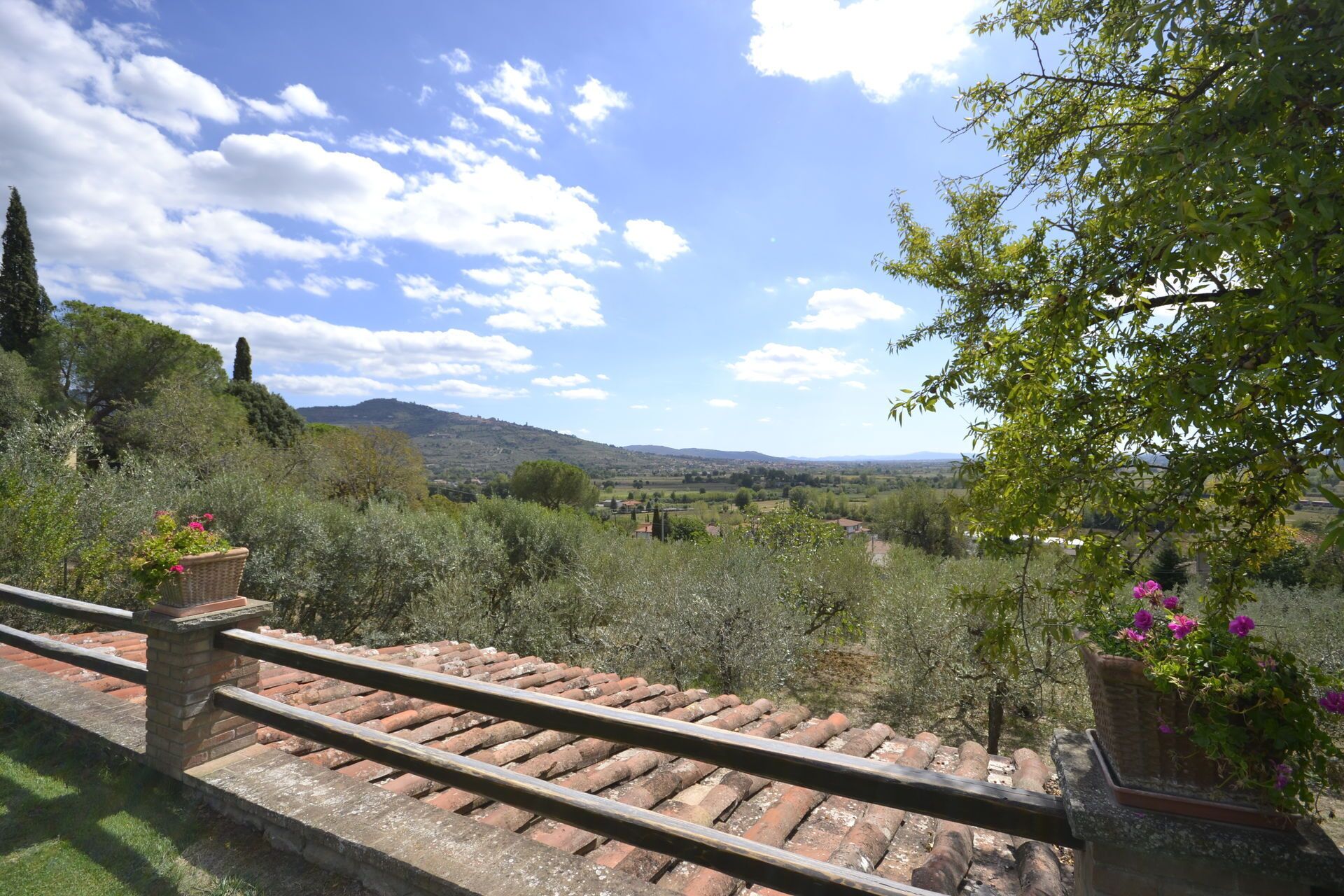 Eine Terrasse mit Blick auf eine ländliche Landschaft, darunter Hügel und ein klarer Himmel.
