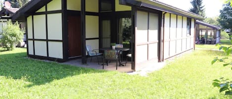 Une maison traditionnelle à colombages dotée d’un patio couvert et d’une table avec des chaises.