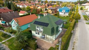 Una casa residencial con paneles solares, techo verde y entrada pavimentada.
