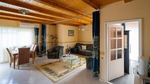 Una sala de estar amplia con techo de madera, un comedor con mesa y sillas, y un sofá.