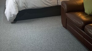 Ein Schlafzimmer mit Bett, einer Couch, einer Lampe und einem Kleiderschrank.